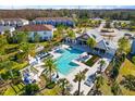 Aerial view of a beautiful community pool with ample seating, palm trees, and a covered lounge area at 3214 Painted Blossom Ct, Lutz, FL 33558