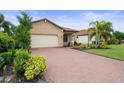 Inviting single-story home with a lush green lawn, brick driveway, a two-car garage, and terracotta-colored tiled roof at 5115 Tobermory Way, Bradenton, FL 34211
