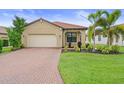 Inviting single-story home with a lush lawn, brick driveway, a two-car garage, and a terracotta-colored tiled roof at 5115 Tobermory Way, Bradenton, FL 34211