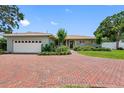Inviting one-story home with a brick driveway leading to an attached garage and beautifully landscaped front yard at 8300 37Th N Ave, St Petersburg, FL 33710