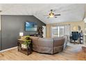 Cozy living room featuring a sectional couch, ceiling fan, wood-look tile floors and backyard access at 8421 Unity Dr, Port Richey, FL 34668