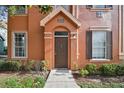 Close-up of a townhouse entrance with a well-maintained door, manicured bushes, and a welcoming path at 9740 Lake Chase Island Way # 9740, Tampa, FL 33626