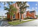 Exterior shot of a charming townhouse with a manicured lawn, mature trees, and a glimpse of a serene lake at 9740 Lake Chase Island Way # 9740, Tampa, FL 33626