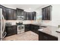 Modern kitchen featuring stainless steel appliances, granite countertops, dark cabinetry, and tile backsplash at 12402 Fairlawn Dr, Riverview, FL 33579