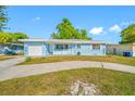 Charming light blue home with attached garage and manicured lawn on a sunny day at 1431 Kings Hwy, Clearwater, FL 33755