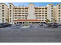 Multi-story condo building with a white facade, red tile roof, and parking area in front at 17717 Gulf Blvd # 702, Redington Shores, FL 33708