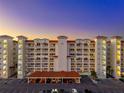 Exterior shot of a condo building with balconies, covered parking, and a blue and orange sunset sky at 17717 Gulf Blvd # 702, Redington Shores, FL 33708