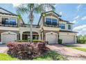 Charming townhome exterior with a two-car garage, beautiful landscaping, and a brick driveway at 18860 Beautyberry Ct, Lutz, FL 33558