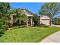 Beautiful home with lush green lawn, mature trees, manicured landscaping, and stone accents at 21627 Pearl Crescent Ct, Land O Lakes, FL 34637