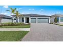 Beautiful single-story home with a two-car garage, brick driveway and a manicured lawn and tropical landscaping at 2731 Winding Creek Trl, North Port, FL 34289