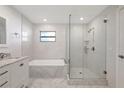 Luxurious bathroom featuring a soaking tub, glass-enclosed shower, and elegant white tile work at 3901 E Eden Roc Cir, Tampa, FL 33634