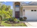 A charming front entrance with a burgundy door, beautiful landscaping, and a festive wreath at 5634 Tanagergrove Way, Lithia, FL 33547