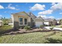 Landscaped front yard of a single-story home with stone accents and a two-car garage at 7740 Blue Spring Dr, Land O Lakes, FL 34637