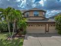Two-story home features a three-car garage, and lush landscaping with mature palm trees at 11308 Callaway Pond Dr, Riverview, FL 33579