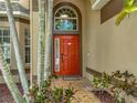 Elegant red front door with decorative sidelight and arched transom window at 11308 Callaway Pond Dr, Riverview, FL 33579