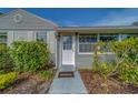 A welcoming front entrance features a white door, sidelight, and neatly trimmed green bushes at 1536 Alamo Ln, Dunedin, FL 34698