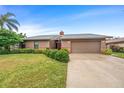 Beautiful single-story home with a lush green lawn, well-manicured bushes, and an attached garage at 1916 38Th W St, Bradenton, FL 34205