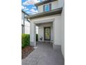 Covered front entrance with a black framed glass door, and a welcome mat on the brick paved entryway at 19592 Breynia Dr, Lutz, FL 33558