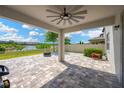 A covered patio with a ceiling fan, and an outdoor kitchen set upon a brick paved surface overlooking the water at 19592 Breynia Dr, Lutz, FL 33558