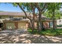 Charming home with a brick facade, mature trees, and a two-car garage on a paver driveway at 21 Pelican Pl, Belleair, FL 33756