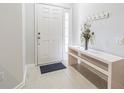 Bright entryway with white walls, ceramic tile floors, and a white bench with a floral arrangement at 4603 Barnstead Dr, Riverview, FL 33578