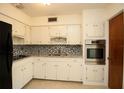 Charming kitchen featuring all white cabinetry, stainless steel appliances and mosaic tile backsplash at 721 75Th N Ave, St Petersburg, FL 33702