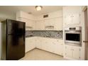 Well-lit kitchen with white cabinetry, modern appliances, mosaic backsplash and neutral flooring at 721 75Th N Ave, St Petersburg, FL 33702