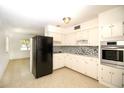 Bright kitchen featuring all white cabinets, modern stainless appliances and mosaic tile backsplash at 721 75Th N Ave, St Petersburg, FL 33702