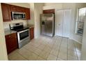 Well-lit kitchen with stainless steel appliances, wood cabinets, tile flooring, and a pantry at 8608 Twin Farms Pl, Tampa, FL 33635