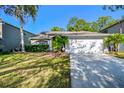 Inviting one-story home with a lush green lawn, mature palm trees, and an attached two-car garage at 12929 Royal George Ave, Odessa, FL 33556