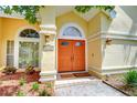 Charming home entrance with an orange double door, arched windows, and elegant exterior lighting at 14119 Stonegate Dr, Tampa, FL 33624