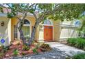 Close-up of the front entrance featuring an orange double door, arched windows, and tasteful landscaping at 14119 Stonegate Dr, Tampa, FL 33624