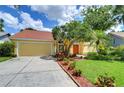 Inviting single-story home showcasing well-maintained landscaping, a driveway, and a cheerful yellow exterior at 14119 Stonegate Dr, Tampa, FL 33624