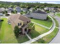 An aerial view of a tan two-story home with a well-manicured lawn and beautiful landscaping at 21046 Passive Porch Dr, Land O Lakes, FL 34637