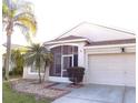 Attractive single-story home boasts a screened-in entryway and a two-car garage, enhanced by palm trees at 25417 Lexington Oaks Blvd, Wesley Chapel, FL 33544