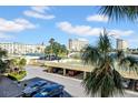 Scenic view of the condo complex featuring covered parking, tennis courts, and lush tropical landscaping at 4725 Cove Cir # 302, St Petersburg, FL 33708