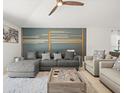 Comfortable living room with modern decor, gray sectional sofa, accent wall, and a ceiling fan at 9617 Branching Ship Trce, Wesley Chapel, FL 33545