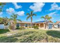 Inviting single-story home with manicured lawn, mature palms, neutral color scheme, and arched entryway at 1012 Spindle Palm Way, Apollo Beach, FL 33572