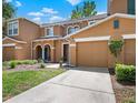 Inviting two-story townhome with an attached two-car garage, manicured lawn, and walkway leading to the front door at 10849 Kensington Park Ave, Riverview, FL 33578