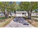 Charming single-story home with a neatly kept front yard, framed by mature trees and a private driveway at 129 Nw Lincoln N Cir, St Petersburg, FL 33702