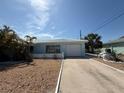 Light blue single-story home with well-manicured stone garden and attached garage with a clean driveway at 195 45Th Ave, St Pete Beach, FL 33706