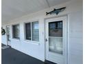 Exterior view of a building with white walls, windows, and a front door with a shark decoration on the wall at 2077 Canal Dr # L35, Bradenton, FL 34207
