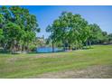 Expansive green backyard with mature trees and a view of the lake at 2344 Pleasant Hill Ln, Holiday, FL 34691