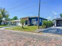 Quaint blue home with modern touches, surrounded by a lush lawn, and a brick-paved street at 2711 W Cordelia St, Tampa, FL 33607