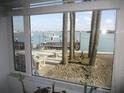 Inviting waterfront view from the window showcases a dock with a boat and swaying palm trees, enhancing the property's appeal at 280 126Th Ave # 106, Treasure Island, FL 33706