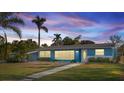 Charming blue single-story home at dusk featuring a well-manicured front yard and lush landscaping at 3500 Gussie St, Punta Gorda, FL 33950