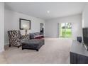 Bright living room with a sliding glass door to the backyard, plush carpeting, and stylish decor at 3686 Zephyr Preserve Pl, Zephyrhills, FL 33541