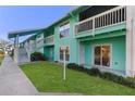 Charming two-story condo building with light-blue siding, green lawn, and a cozy outdoor porch with sliding glass door at 455 Alt 19 # 111, Palm Harbor, FL 34683