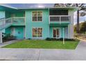 Beautiful two-story condo building with light-blue siding, green lawn, white doors and stairs, and covered outdoor porches at 455 Alt 19 # 111, Palm Harbor, FL 34683
