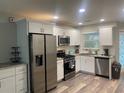 Modern kitchen featuring stainless steel appliances, white cabinetry, and hardwood floors at 4551 Floramar Ter, New Port Richey, FL 34652